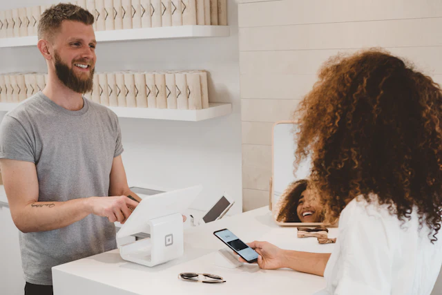 Young shop owner taking a card payment with a smile